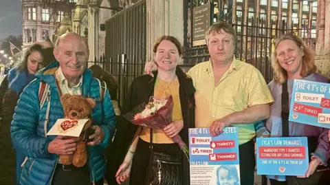 Carla Green / BBC Four people stood outside of Parliament with signs.