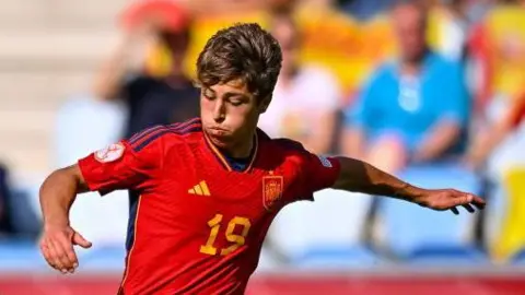 Lluc Castell in match action for Spain under-17s in a red Spain match shirt with the number 19 in gold in the middle of the shirt