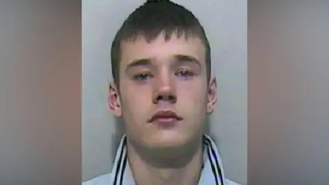 Lancashire Police A mugshot of a young man wearing a blue polo shirt with the collar unfolded upwards.