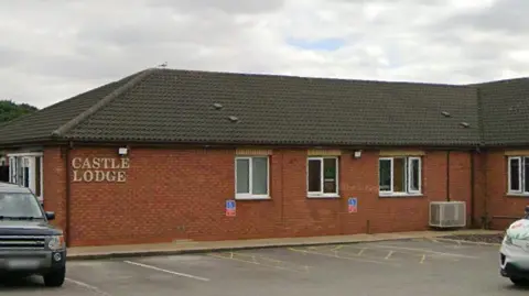 The exterior of Castle Lodge Independent Hospital in Bransholme. It is a long, single-storey building with windows. A car park is in front of it.