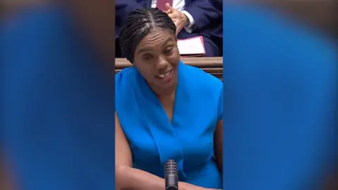 Leader of the opposition Kemi Badenoch wearing blue dress