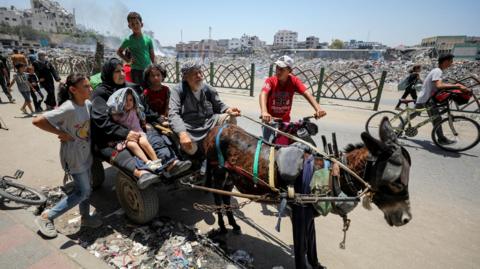 A Palestinian family sits on a donkey-pulled cart as they flee their homes in the Shejaiya area of Gaza City following Israeli bombardment (27 June 2024)