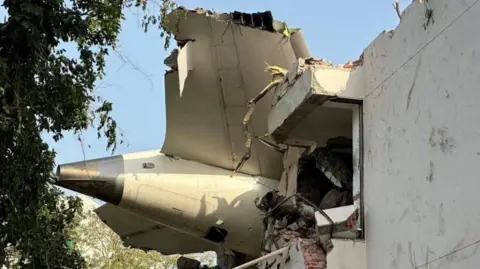 The tail of an aircraft is seen protruding out of the rubble of a building in Ahmedabad, India. 
