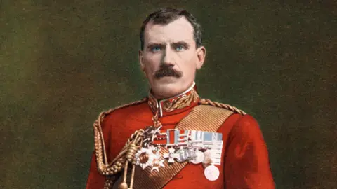 Getty Images Maj Gen Sir Hector MacDonald is a stern looking man with dark hair and moustache, and blue eyes. He is wearing a red military dress uniform with a high collar and a row of medals pinned to his chest. 