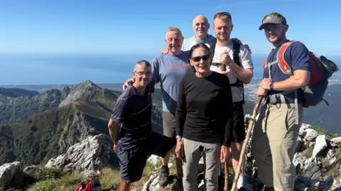 Supplied Rob Hann is pictured on a mountain top with his two sons and the three members of his father's comrade 