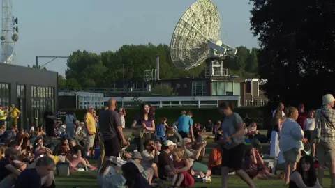 People view the eclipse with the dish of Jodrell Bank radio telescope in the background.