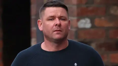 Reuters Peter Spooner, with short brown hair gelled to one side and wearing a blue sweatshirt, arrives at the coroner's court.