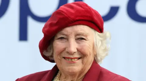 Dame Vera Lynn wearing a red blazer and red beret.
