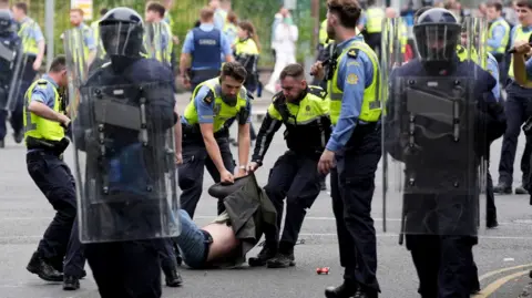 PA Media Man op de grond met zijn jas over zijn hoofd getrokken door Ierse politieagenten