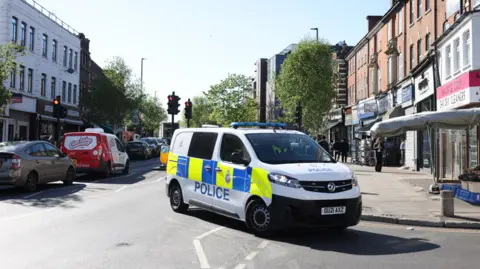 A Police van outside a row of shops in Golders Green, near to where two men were stabbed on 29th April.