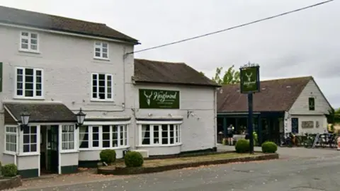A large white building with a brown tiled roof and large bay windows and two green signs which both read The Haughmond