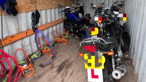 Chris Ganley A set of motorbikes are seen parked inside a lock-up style facility with a wooden floor and corrugated iron walls