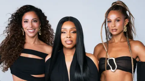 Mis-Teeq pictured against a light blue background. Left to right: Su-Elise, Sabrina and Alesha