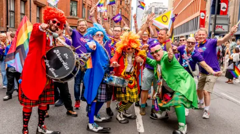 Getty Images A group of people, wearing colourful costumes, have gathered together during the parade in Manchester for the photograph. 