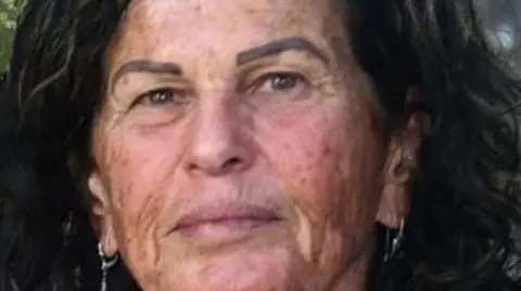 The Hostages and Missing Families Forum An image of Ofra Keidar. She is looking directly at the camera, has black frizzy hair and earrings.
