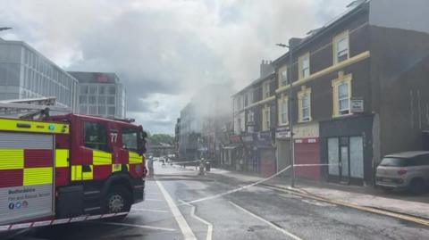 Fire engines in street with premises on fire