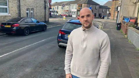 Sam Bevan standing next to a road
