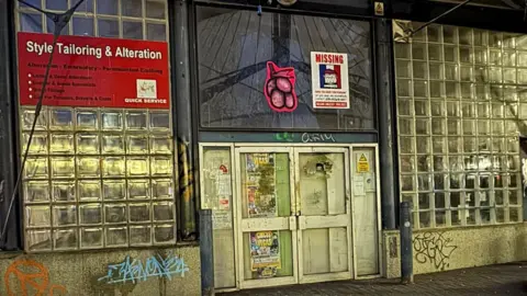 Chrisha Góes The same wall with grey brickwork and small glass squares with less graffiti in darker light
