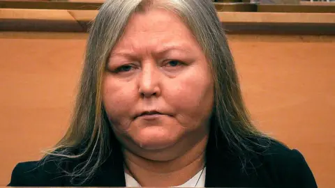 Firecrast \ BBC photo of Donna brand in court. He has long hair that is getting gray and wearing a black jacket. 