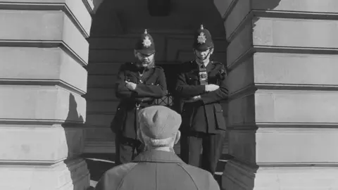 John Dean Two policemen talking to an old man in a flat cap outside Nottingham Council House
