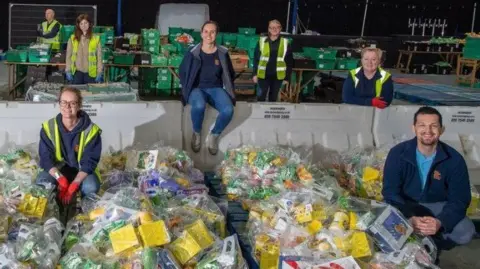 Volunteers wearing yellow hi-vis jackets at a food hub.