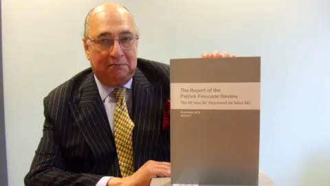 PA Sir Desmond de Silva holding up document entitled "The Report of the Patrick Finucane Review"