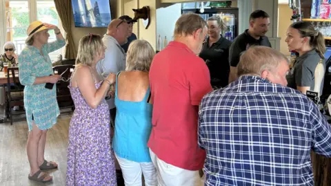 Adam Nicoll A group of people queuing up to buy drinks in a pub