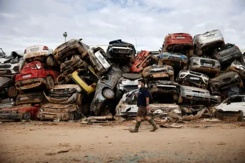 BIEL ALINO/EPA-EFE A man tries to find his vehicle in an improvised junkyard in the flood-hit municipality of Massanassa, province of Valencia, Spain