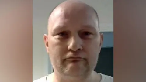 Edwin Newman, a 45-year-old bald man with greying stubble.