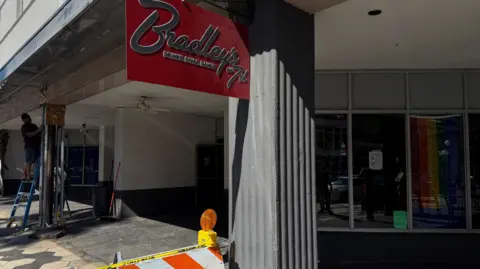 Reuters The empty front of the bar, with Bradley's sign hanging above and some police tape 