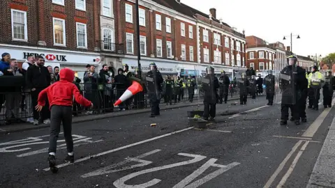 Riot Police are seen on Epsom high street as people throw objects towards them