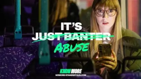 South Yorkshire Police's poster for its Know More campaign calls out online abuse and harassment aimed at women and girls. The poster shows a girl with long hair and glasses sitting on a bus in the dark. Her face is lit by her phone. White writing saying 'It's just banter' has been crossed out and replaced with 'It's abuse'. Know More: Stand With Us branding is at the bottom with the website (nomore-standwithus.com)