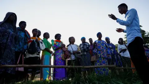 Reuters A Ugandan polling agent talks to a group of female voters at a polling station.
