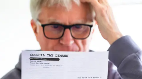 Man in glasses reads a council tax demand.
