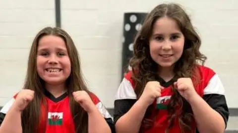 Lili-Rose and Annarose pose for a photo in their Team Wales tracksuits 