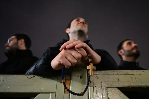 AFP A priest holds a rosary at St Peter's basilica before prayers for the health of Pope Francis at The Vatican on on 24 February 2025.