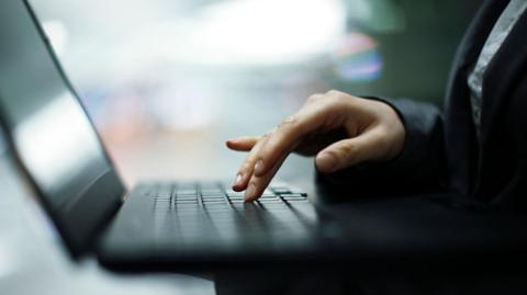 A hand hovering over a laptop computer 
