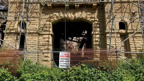 A fenced-off stone archway in one of the mill buildings