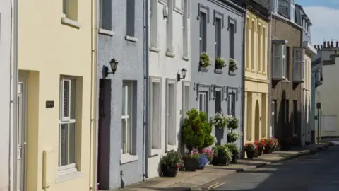 The High Street, a road with colourful buildings and plants outside.
