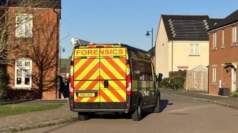 A police forensics van is parked on a residential estate on a sunny day. 
