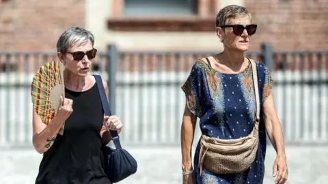 A person uses a fan on a hot summer day in Milan, Italy, 31 July 2026