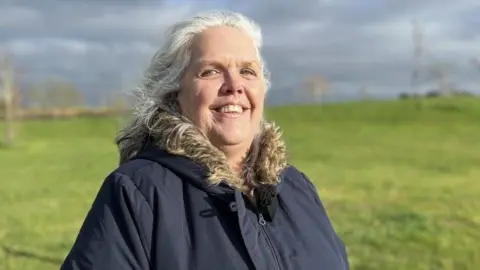 Paulette Bennett in a dark coat standing in an open field