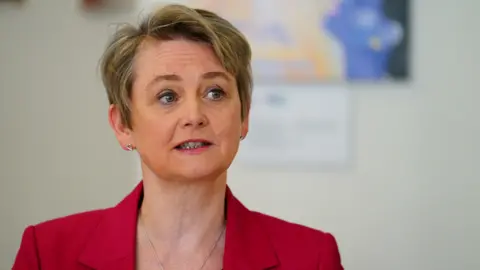 Sekretaris Rumah Media PA Yvette Cooper mengenakan setelan merah