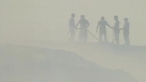 Firefighters working on heathland, through a haze of smoke.