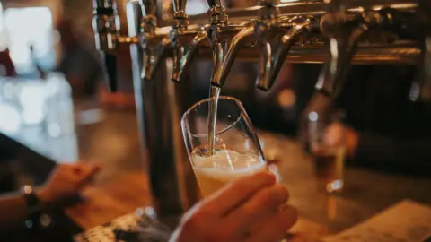 A drink is being poured from taps in a pub - it is a generic shot.