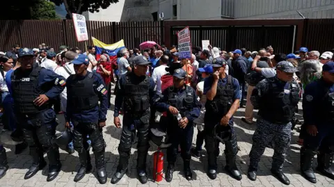 AFP via Getty Images Venezuelan policemen stand in front of a protest in Caracas over low wages