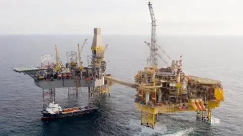 An oil rig out in the North Sea - two platforms with a small boat beside them