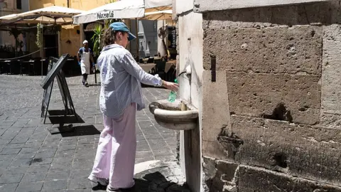 A woman filling up a water bottle in a public tap