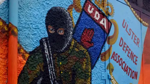 Pacemaker A Mural featuring a masked soldier and painted UDA crest with the red hand in the centre.