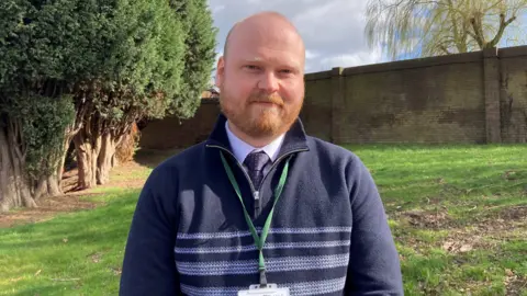 Adam Smith - a Redditch Borough Council worker - is stood in a large field at Abbey Cemetery. 
